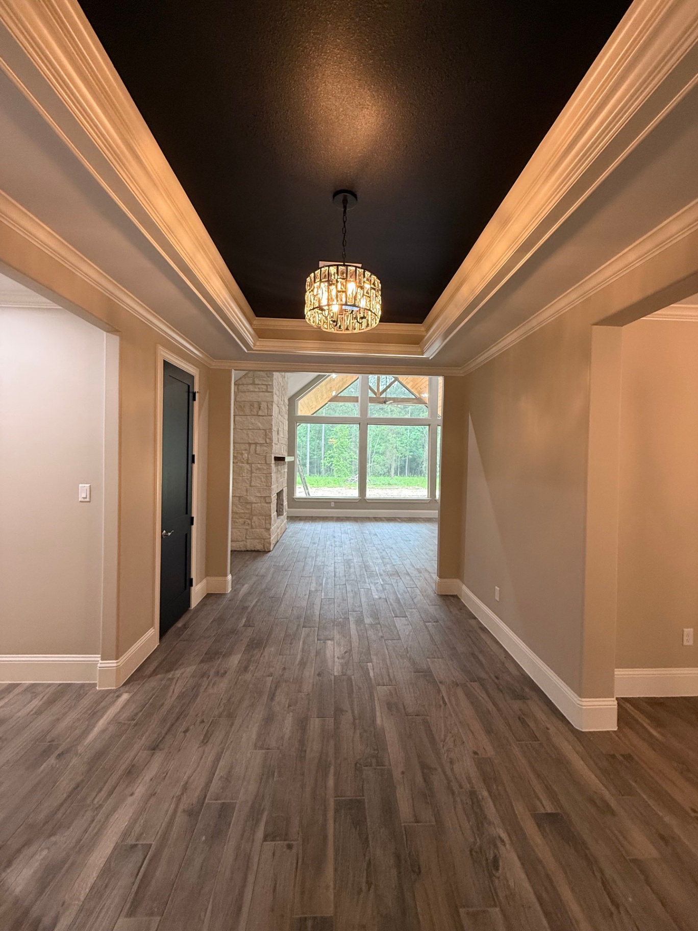 Long entry hall with tray ceiling, crown molding, and chandelier
