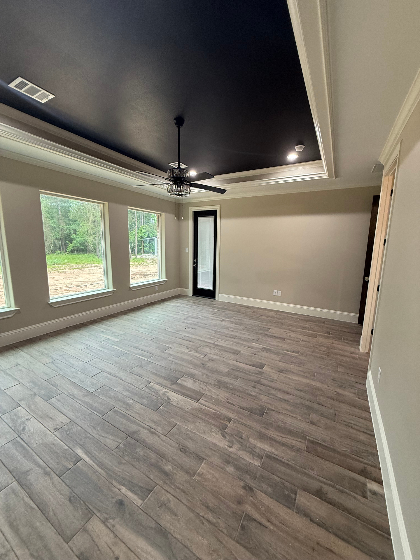 Bedroom with dark tray ceiling, large windows, and black accent wall