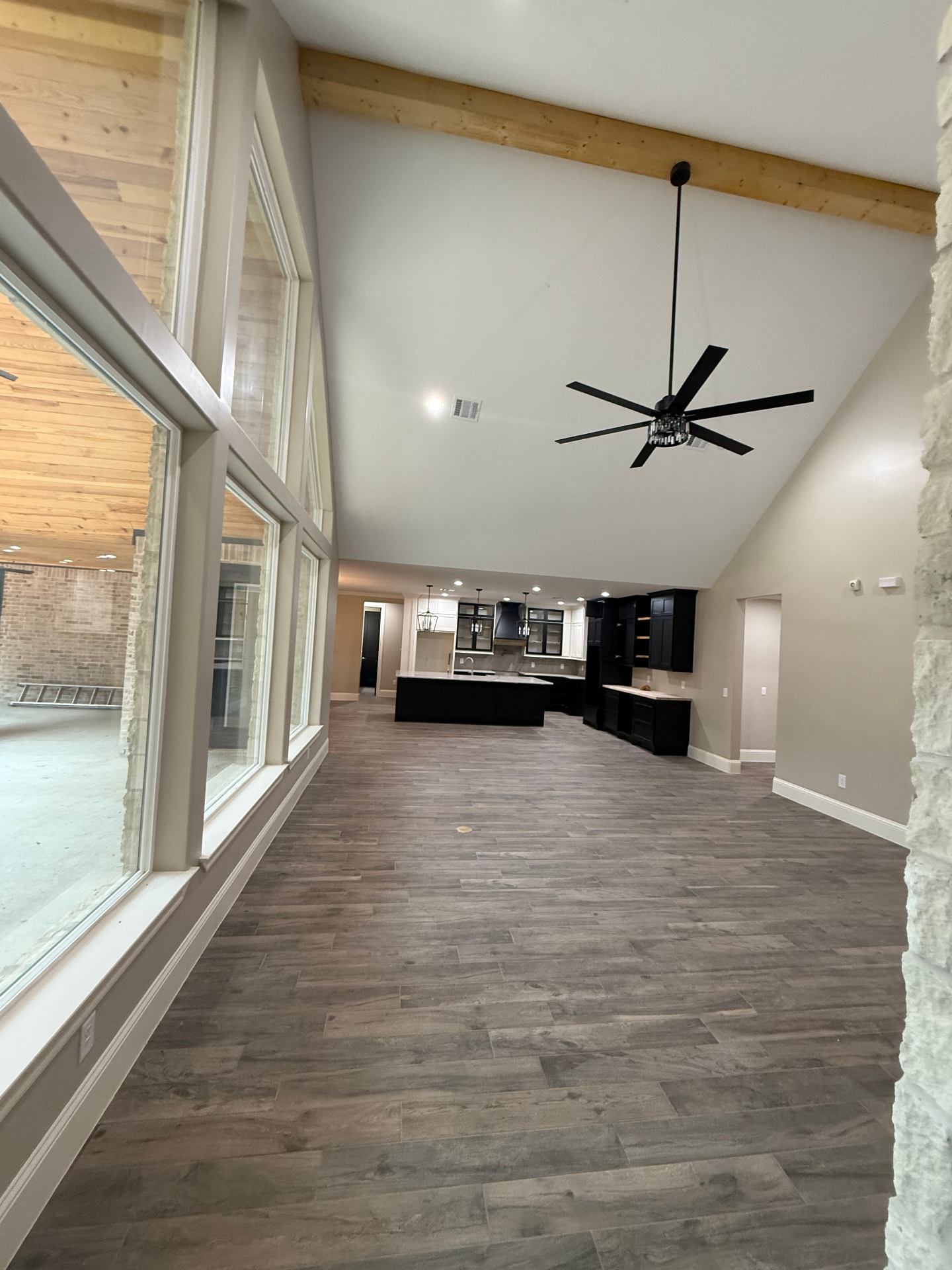 Large open-concept great room with tall windows and kitchen in the background