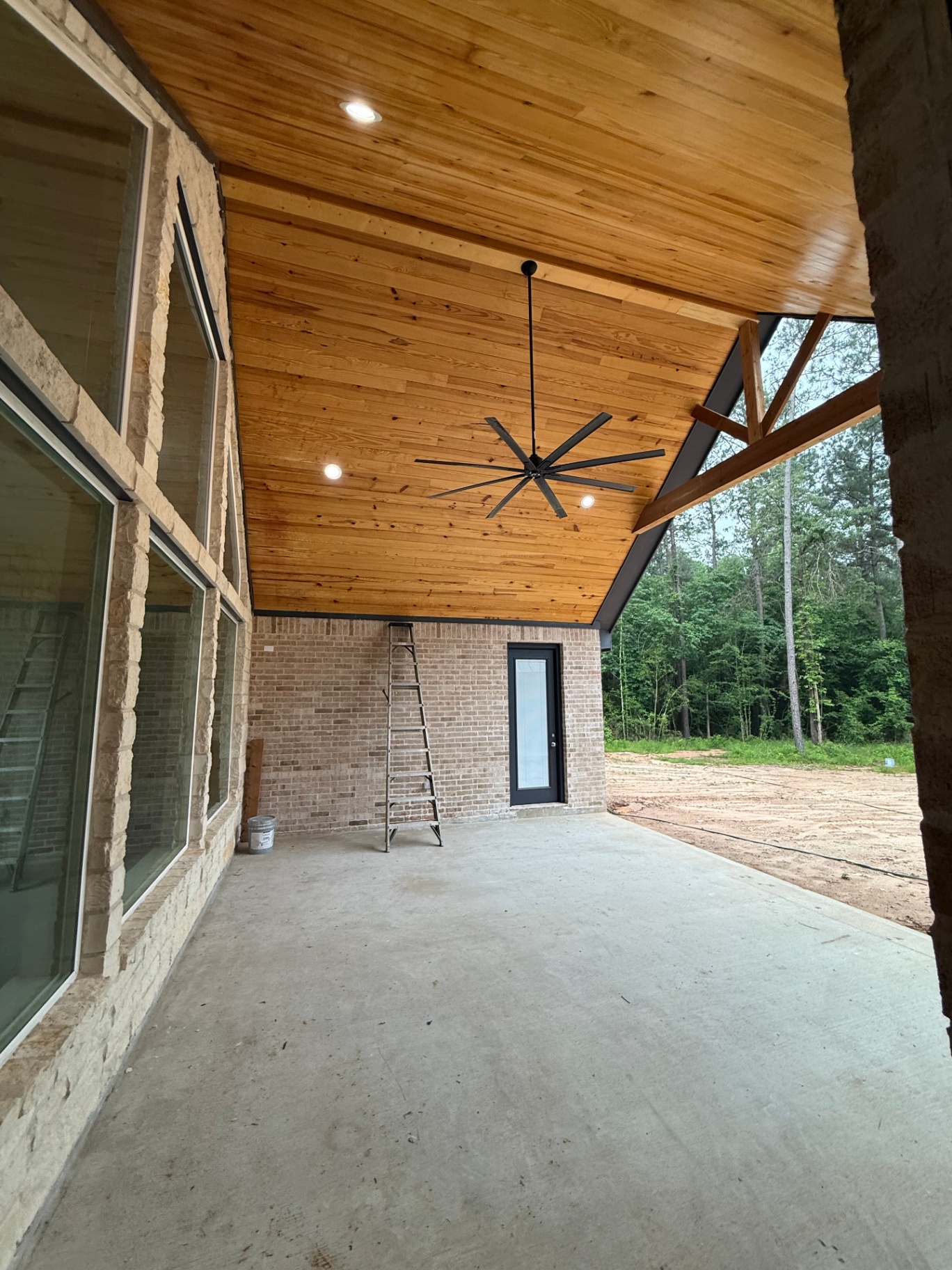 Covered patio with wood ceiling, ceiling fan, and stone exterior details